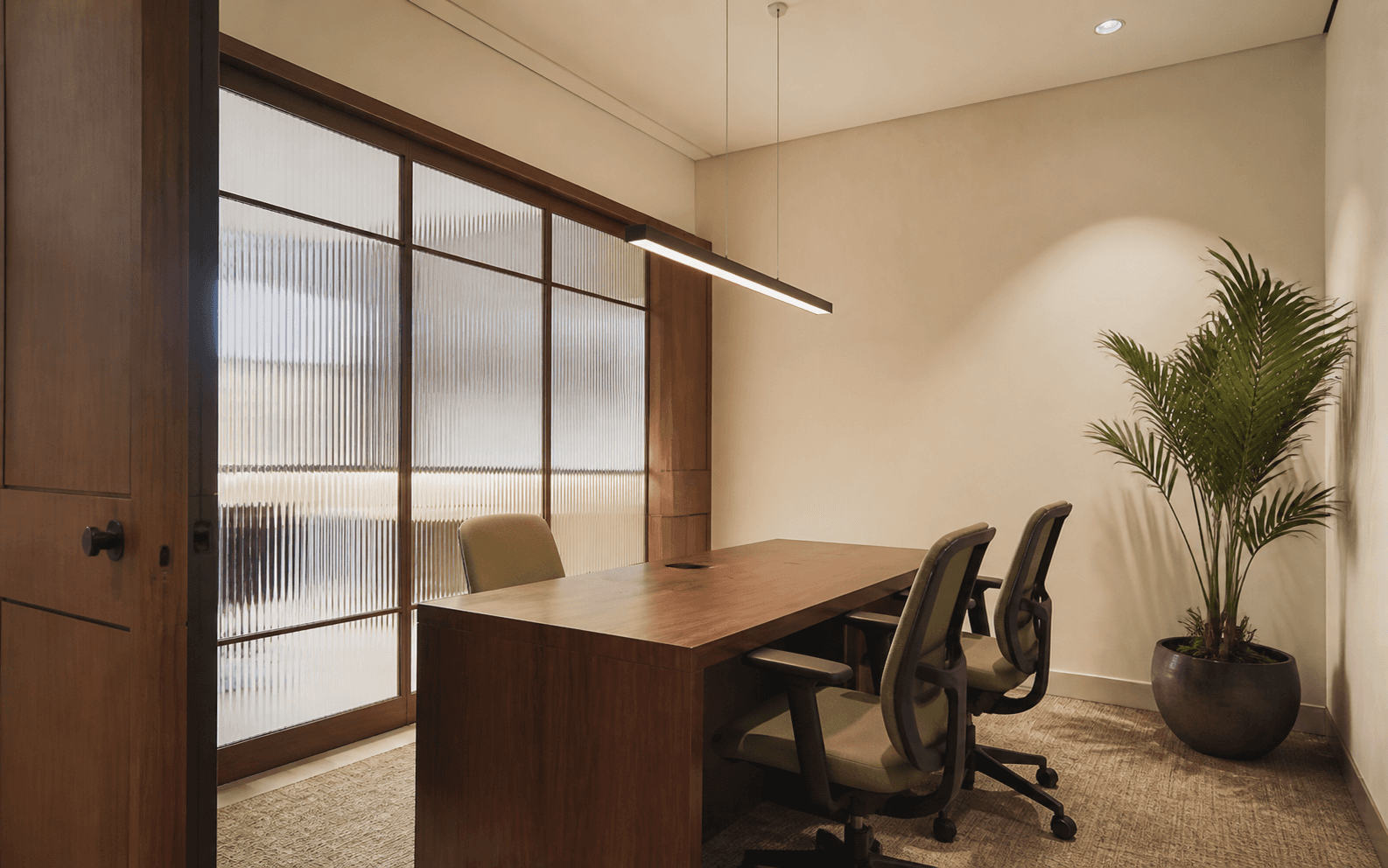 Warm private office with timber table, ergonomic chairs and fluted glass